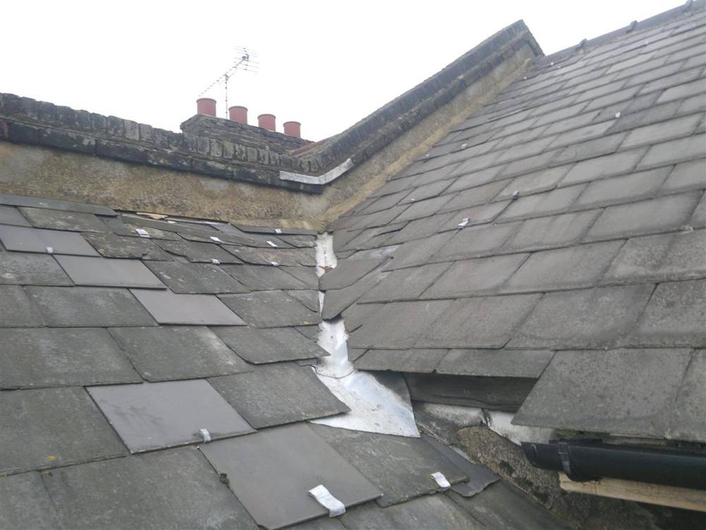 Slipped slates and damaged flashing before repair
